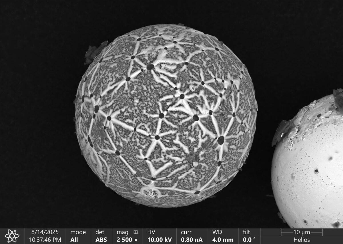 Molten Planets — ultrasonically atomized Al alloy powder particles with core–shell morphology formed by liquid-phase separation during cooling. BSE SEM, Helios FIB-SEM, 10 µm.